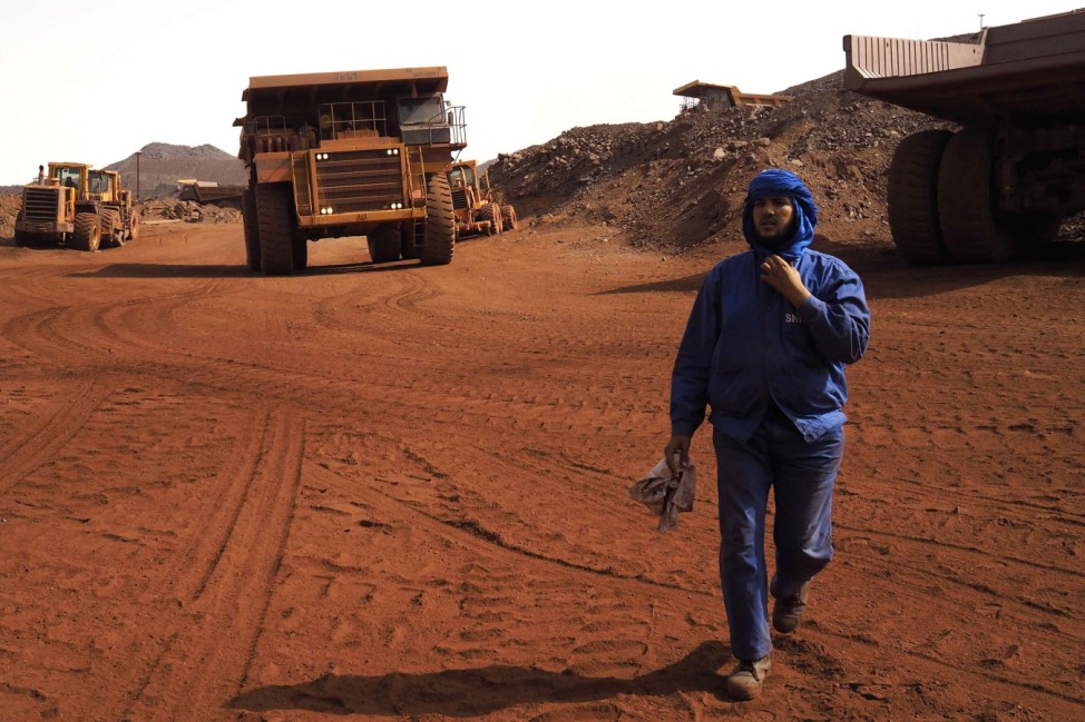 A SNIM truck driver walks in front of trucks at the TO-14 iron ore mine in Zouerate