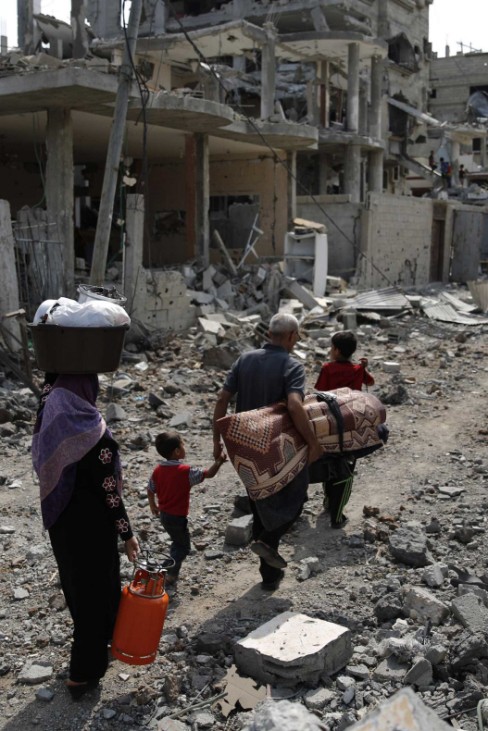 A Palestinian family carries their belongings towards the remains of their destroyed home in the northern Gaza Strip