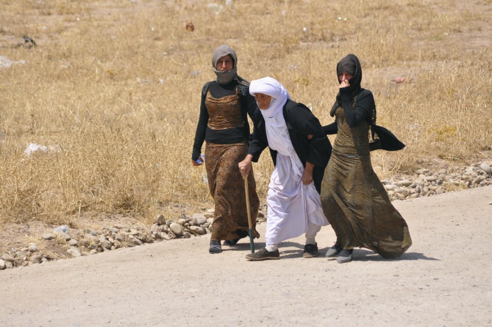 Displaced families from the minority Yazidi sect, fleeing the violence, walk on the outskirts of Sinjar, west of Mosul