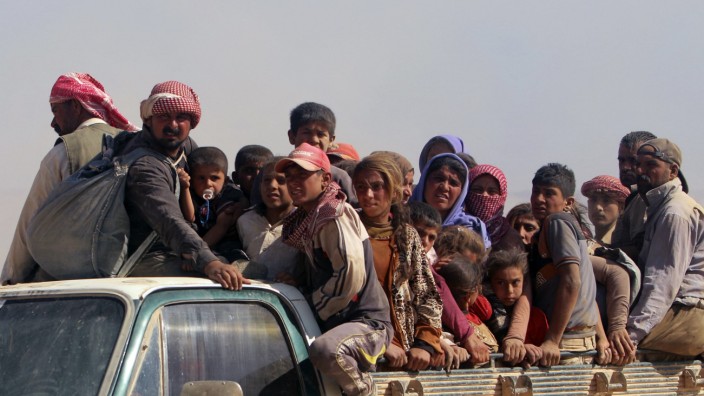 Displaced people from the minority Yazidi sect, fleeing violence from forces loyal to the Islamic State in Sinjar town, ride a truck as they make their way towards the Syrian border, on the outskirts of Sinjar mountain