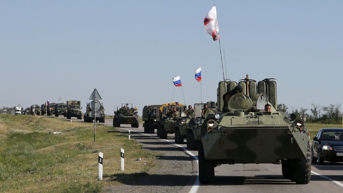 Russian military personnel ride atop APCs outside Kamensk-Shakhtinsky