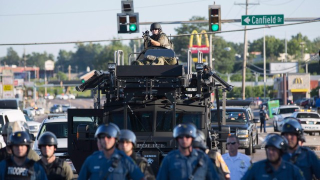 Riot police stand guard as demonstrators protest the shooting death of teenager Michael Brown in Ferguson, Missouri