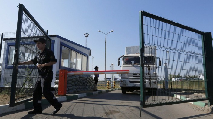 A Russian border guard opens a gate in front of a truck from a convoy that delivered humanitarian aid for Ukraine on its return to Russia at border crossing point 'Donetsk' in Russia's Rostov Region