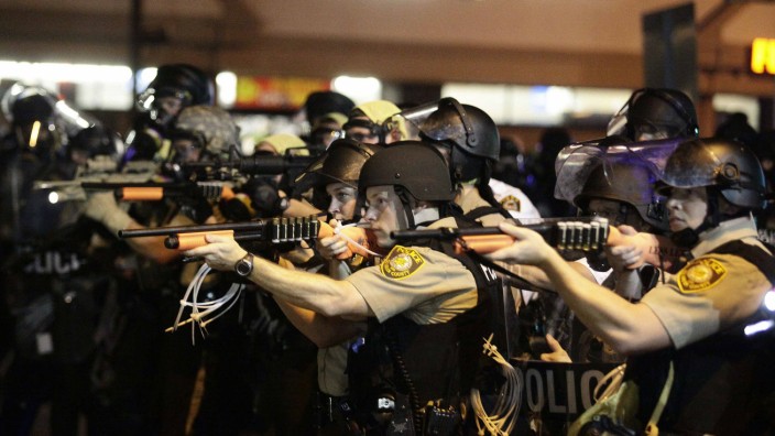 Police officers point their weapons at demonstrators protesting against the shooting death of Michael Brown in Ferguson, Missouri