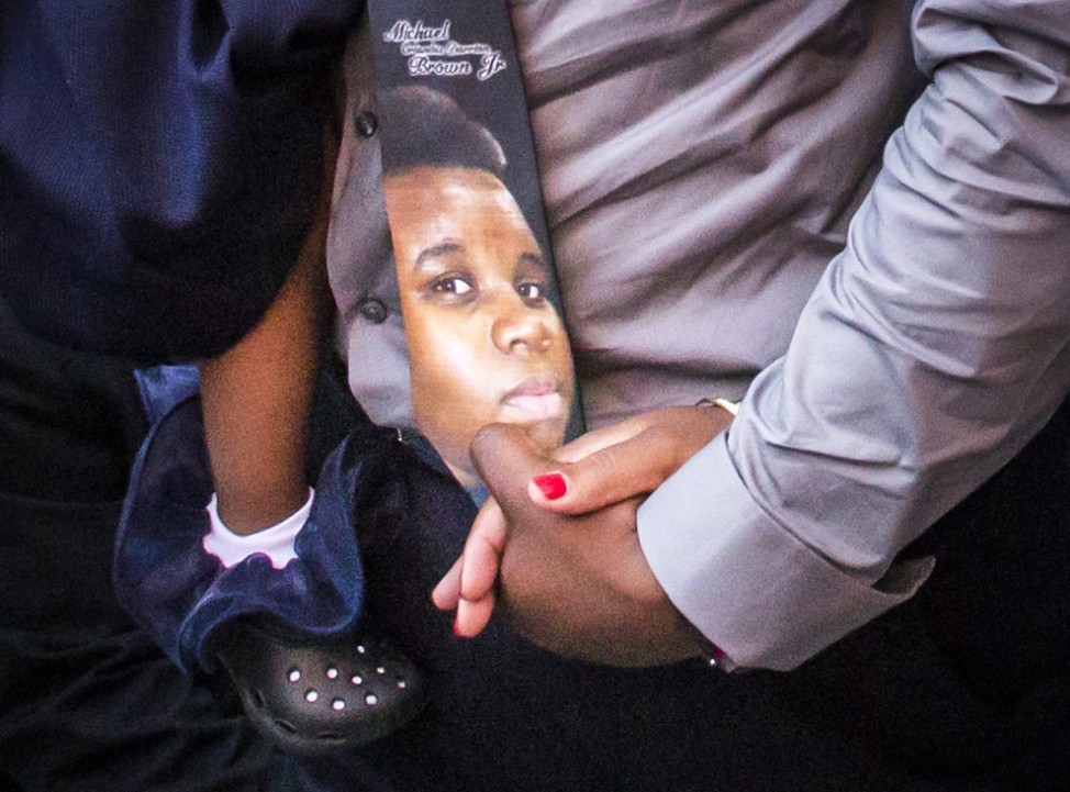 An image of 18-year-old Michael Brown is seen on a tie worn by his father as his parents Lesley McSpadden and Michael Brown Sr., hold hands while arriving to take part in their son's funeral services in St. Louis