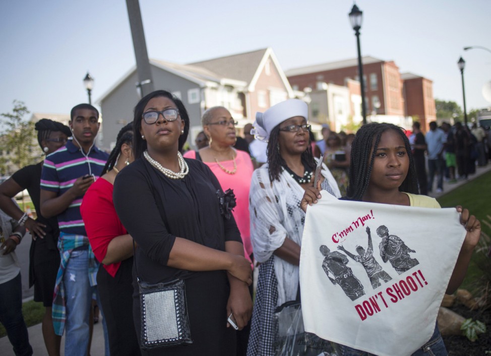 A woman holds a sign while standing in line to take part in the funeral services for 18-year-old Michael Brown at the Friendly Temple Missionary Baptist Church in St. Louis, Missouri,
