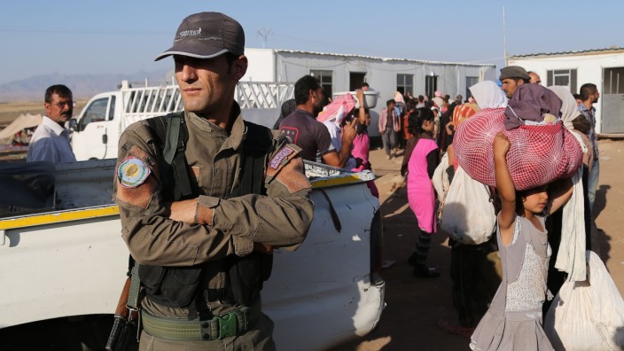 Jesiden und Kurden im Irak: Ein Peschmerga-Kämpfer steht Wache während der Ankunft aus dem Irak vertriebener Jesiden vor einem Flüchtlingslager in Syrien