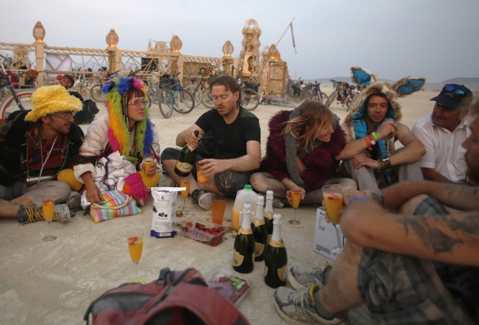 Participants enjoy drinks before sunrise at the Temple of Grace during the Burning Man 2014 'Caravansary' arts and music festival in the Black Rock Desert of Nevada