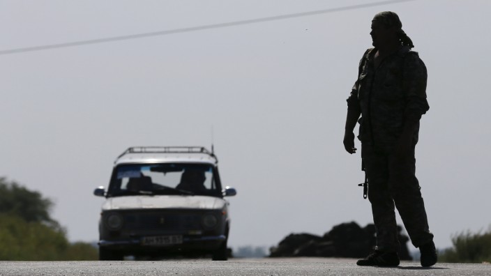 A car moves towards the direction of a pro-Russian separatist at a checkpoint outside the village of Kreminets near the city of Donetsk
