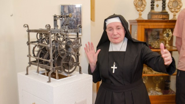 Dietramszell: Schwester Kiliana erklärt die schmiedeeiserne Uhr aus der Zeit um 1700, die ein Pendel in Form eines strahlenumkränzten Herzens hat.