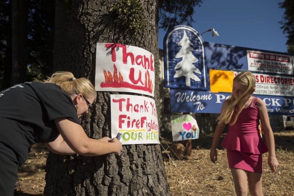 A woman displays a 'thank you' sign for firefighters battling the King Fire in Pollock Pines, California