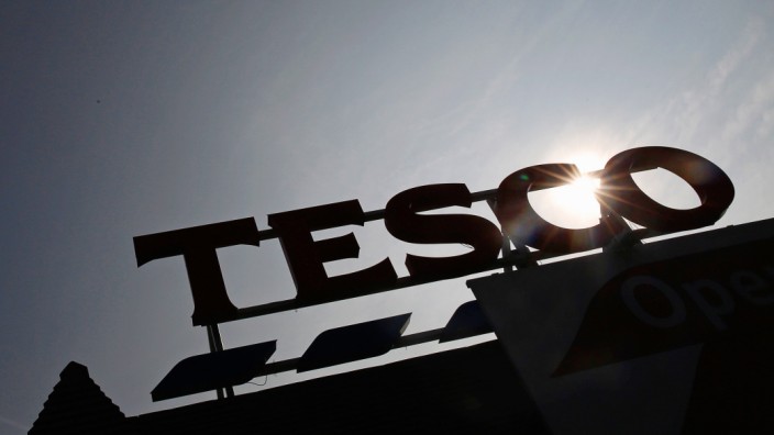 The signage of Tesco Extra is silhouetted against the sun in southwest London