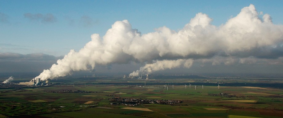 An aerial view shows steam billowing from the cooling towers of a coal power plant in the western town of Neurath