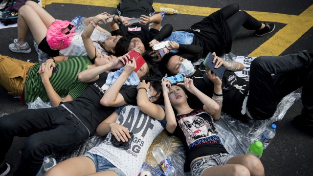 Demonstrationen für mehr Demokratie: Demonstranten liegen während ihrer Blockade in der Nähe des Hongkonger Regierungsviertels auf dem Boden und checken ihre Smartphones
