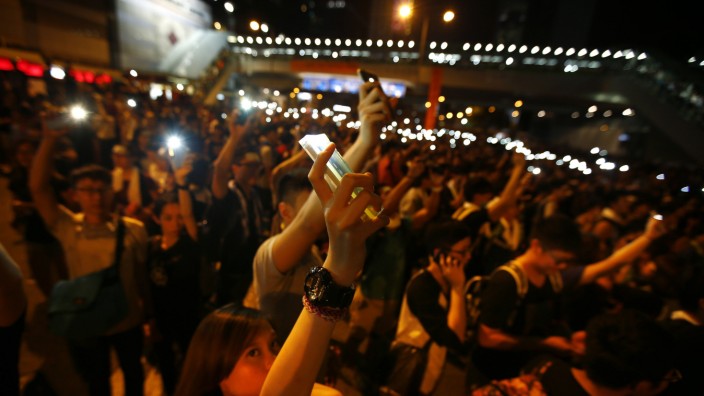 Protesters hold up their mobile phones with the flash light function switched on, as they block the main street to the financial Central district in Hong Kong