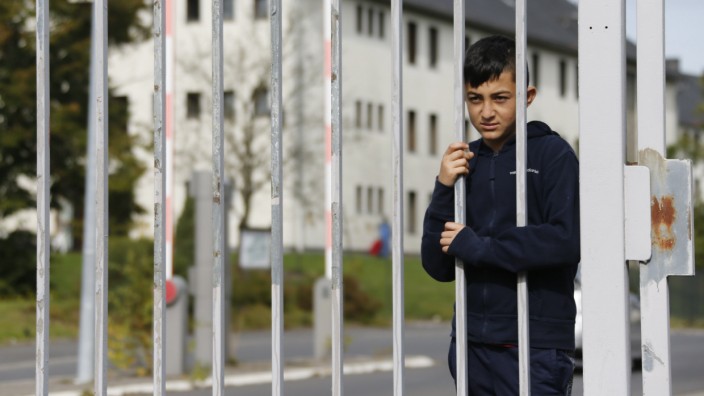 Boy stands behind the gate to home for asylum seekers in Burbach near the western German town of Siegen
