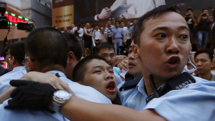 Pro-democracy protester bleeds in the month as he is escorted by the police after being beaten by anti-Occupy Central protesters at Hong Kong's shopping Mongkok district