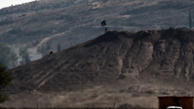 IS-Terrormiliz vor Einnahme von Grenzstadt: An Islamic State (IS) flag is placed on a hill in the Syrian town of Ain al-Arab, known as Kobane by the Kurds, as seen from the Turkish-Syrian border in the southeastern town of Suruc, Sanliurfa province, on October 6, 2014. Two flags of Islamic State (IS) jihadists seeking to take the Syrian town of Kobane were flying on the eastern side of the town, an AFP photographer reported. The flags, black with the Arabic lettering of the group, were seen by the photographer from the Turkish side of the border. One flew on a building while another larger flag was planted on a hill. AFP PHOTO / ARIS MESSINIS