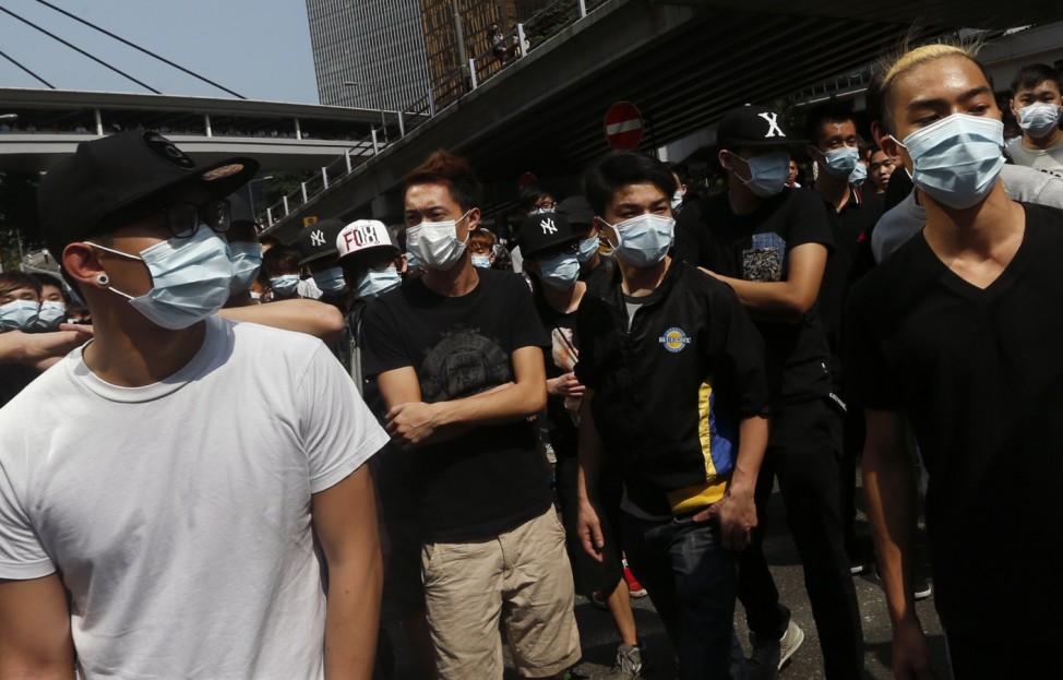Anti-Occupy Central protesters wearing masks stand in front of a police cordon in Hong Kong