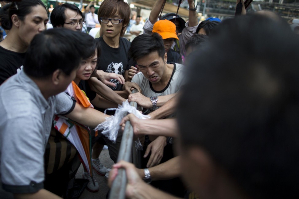 Pro-democracy protesters hang on to their barricades as they clash with anti-Occupy Central protesters in the Central financial district in Hong Kong