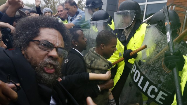 Activist Cornel West is knocked over during a scuffle with police during a protest at the Ferguson Police Department in Ferguson