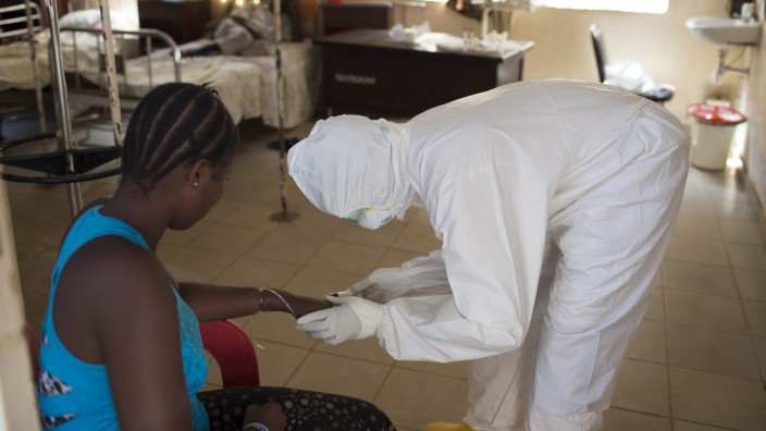Health worker wearing protective equipment takes a blood sample from a patient at a ward for patients suspected of having the Ebola virus, at Rokupa Hospital