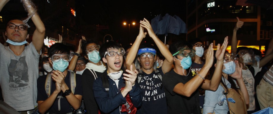 Pro-democracy protesters applaud after riot police retreated from a main road at Mong Kok shopping district in Hong Kong