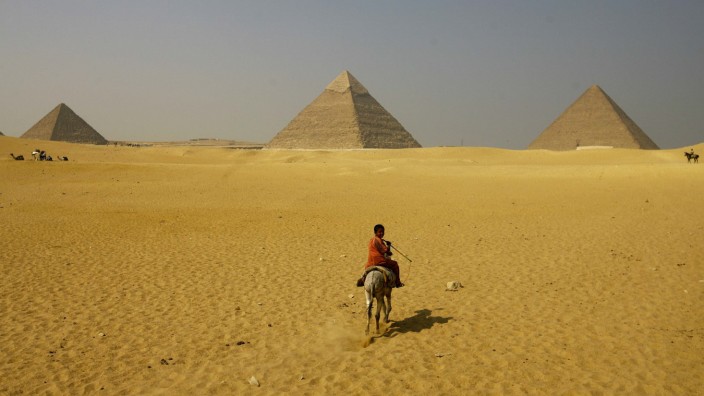 A boy rides a horse in front of the Great Pyramids of Giza on the outskirts of Cairo