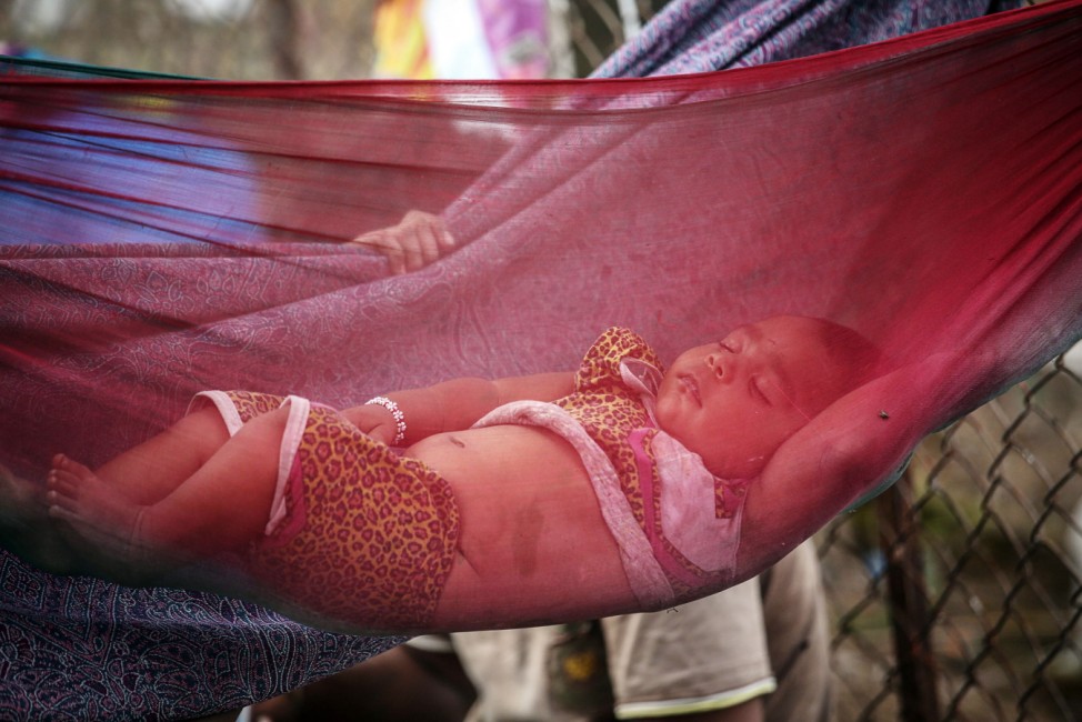 A baby sleeps in a hammock on the roadside in Mumbai