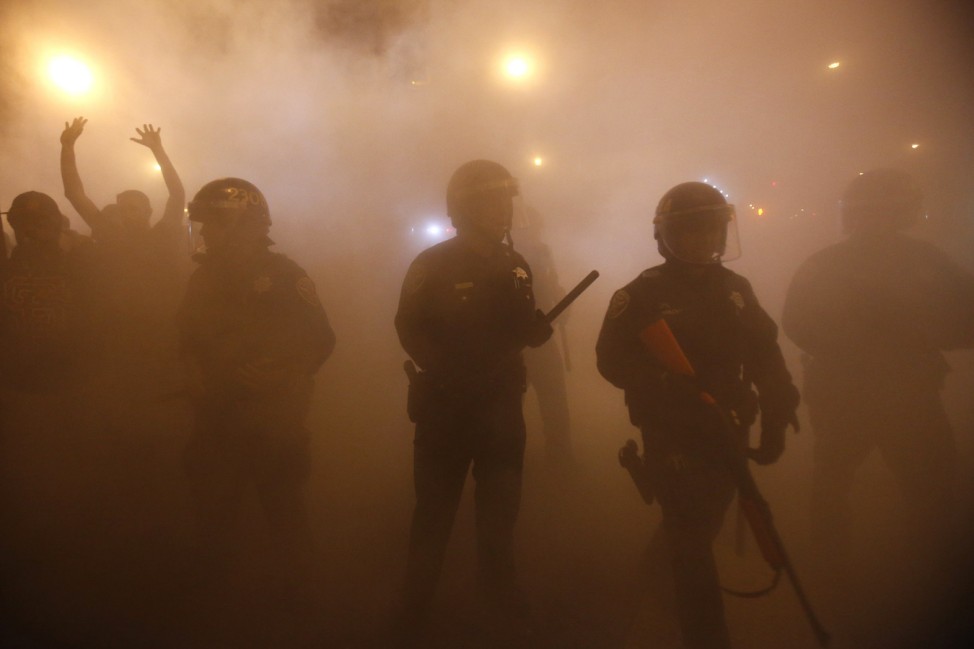 Police officers walk through smoke from a bonfire during a street celebration in San Francisco