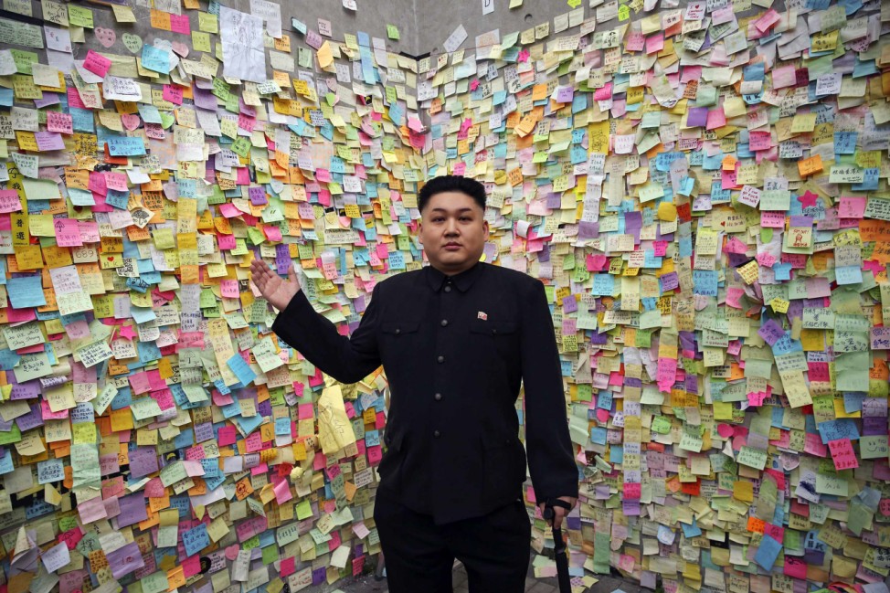 Howard, a 35-year-old Australian Chinese musician and lookalike of North Korean leader Kim Jong Un, gestures in front of a wall with messages of support to pro-democracy protesters in part of Hong Kong's financial central district they are occupying