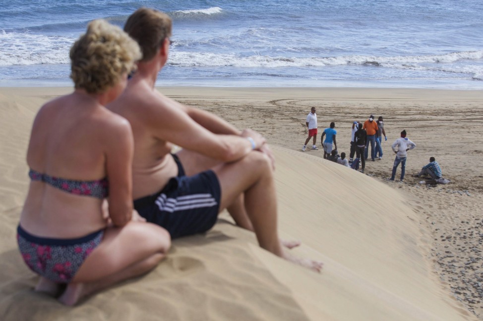 Tourists look at would-be immigrants at the Maspalomas beach, on Gran Canaria in Spain's Canary Islands
