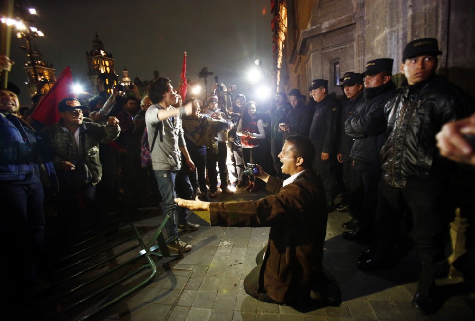 A member of security kneels on the ground trying to calm protesters outside Mexican President Enrique Pena Nieto's ceremonial palace during a protest denouncing the apparent massacre of 43 trainee teachers, in the historic center of Mexico City