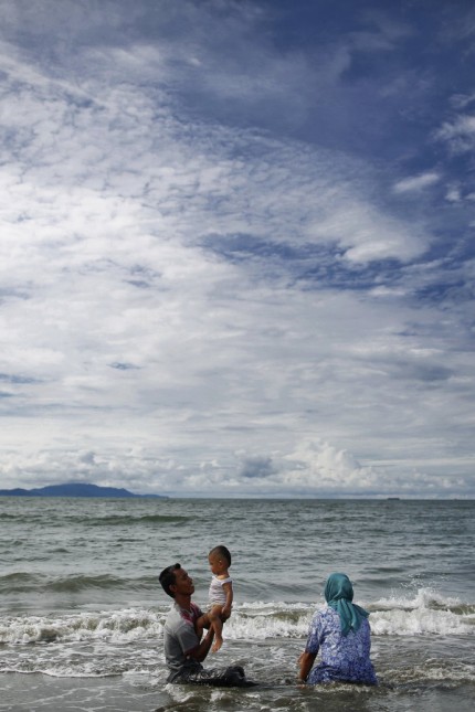 A Muslim family enjoys nice weather on the beach in Banda Aceh