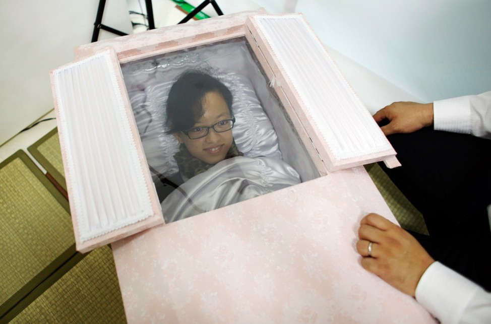 Natsumi Niki smiles as she lies in a coffin to test it during an end-of-life seminar held by Japan's largest retailer Aeon Co in Tokyo
