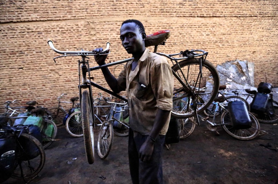 A man carries his bicycle over his shoulder after making his delivery of used oil in the capital Khartoum