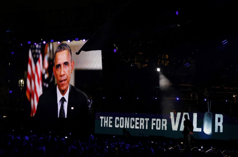 U.S. President Barack Obama addresses the crowd on a video screen during the start of The Concert for Valor on the National Mall on Veterans' Day in Washington