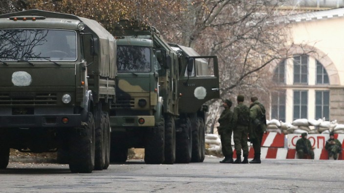 Armed people and military trucks are seen near a checkpoint outside a building on the territory controlled by the self-proclaimed Donetsk People's Republic in Donetsk