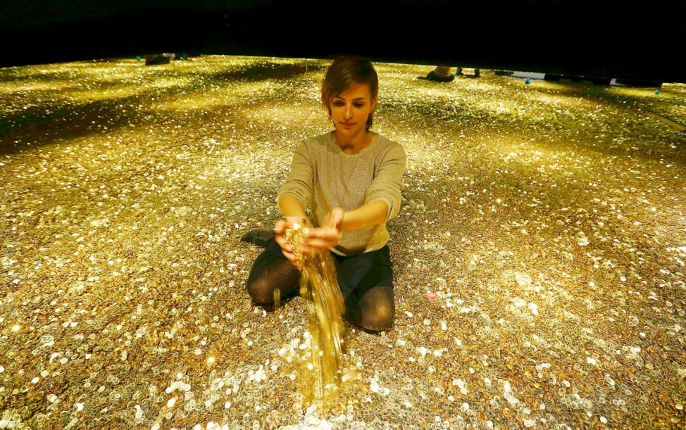 Enz of the Stapferhaus, an event place for contemporary exhibitions, holds coins in her hands as she sits in a room filled with 4 million Swiss five cent coins during the exhibition 'Geld - Jenseits von Gut und Boese' in Lenzburg