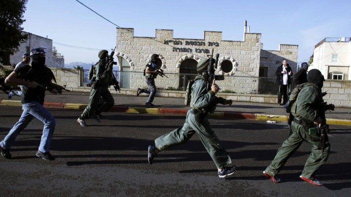 Israeli security personnel run next to a synagogue, where a suspected Palestinian attack took place, in Jerusalem