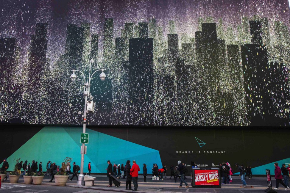 Pedestrians walk underneath a giant new advertising screen in Times Square, New York