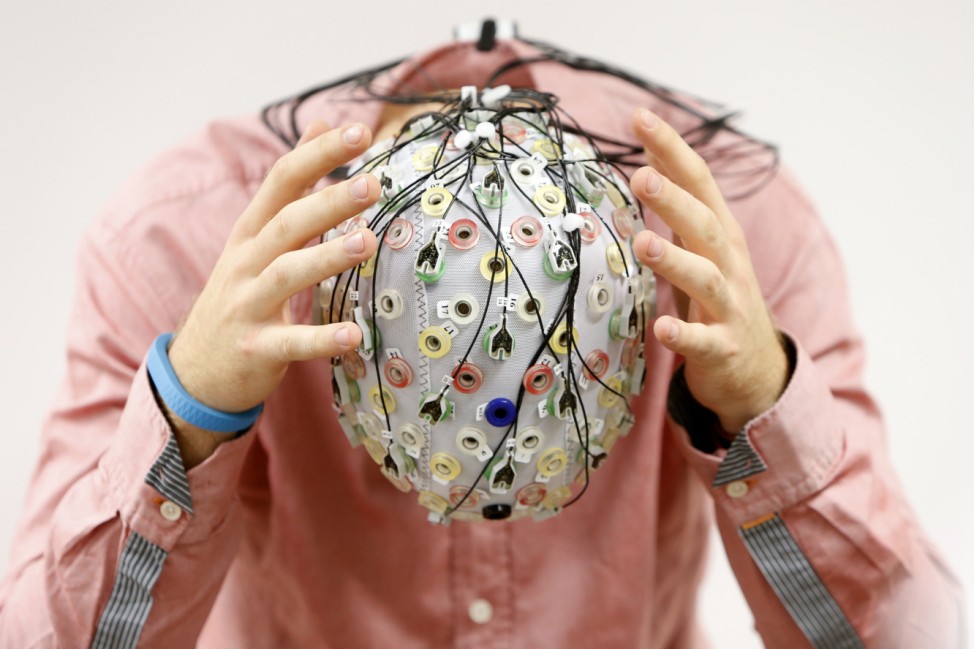 Test person Thiel poses with an electroencephalography cap which measures brain activity, at the Technische Universitaet Muenchen in Garching