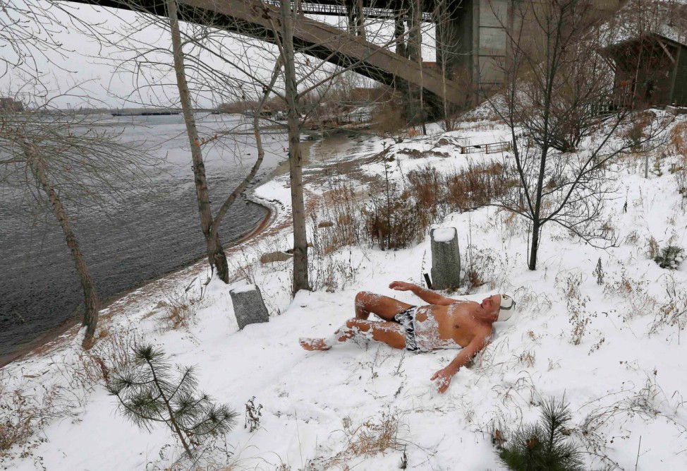 Abrosimov, 78, a member of a local winter swimmers' club, rolls around in snow before bathing in the Yenisei River