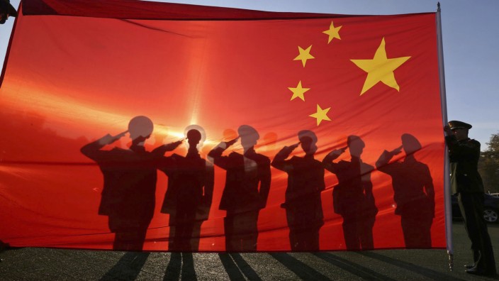 Retired paramilitary policemen, who conduct the daily national flag raising and lowering ceremony on Tiananmen Square, salute to a Chinese national flag