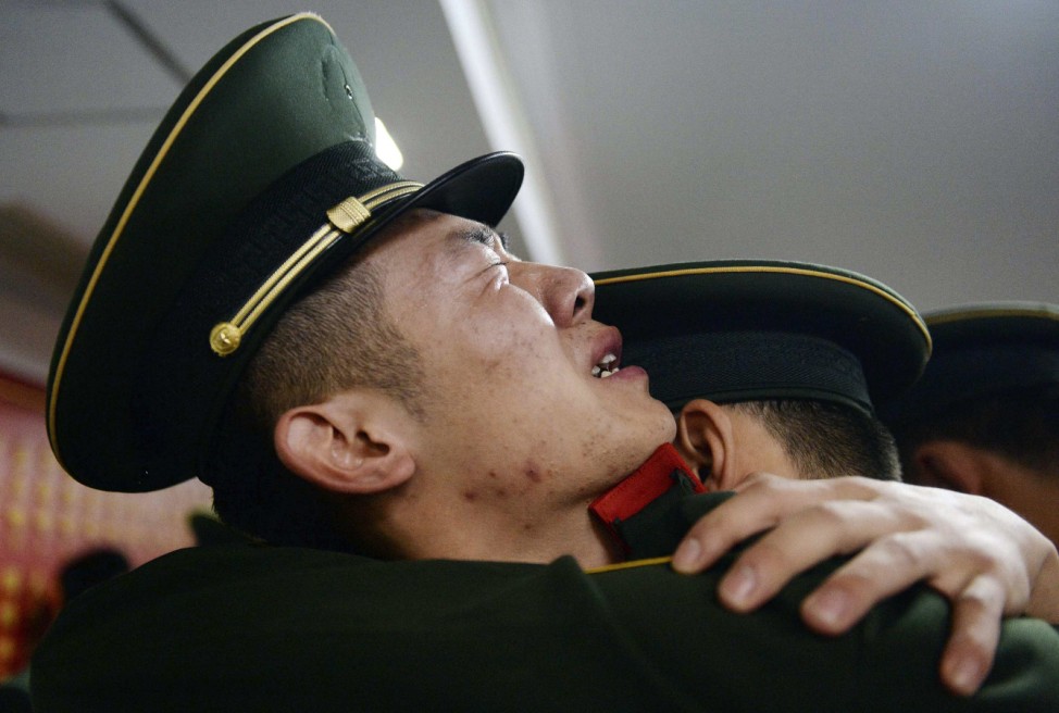 A retired paramilitary policeman cries as he hugs his comrade during a farewell ceremony in Shanghai