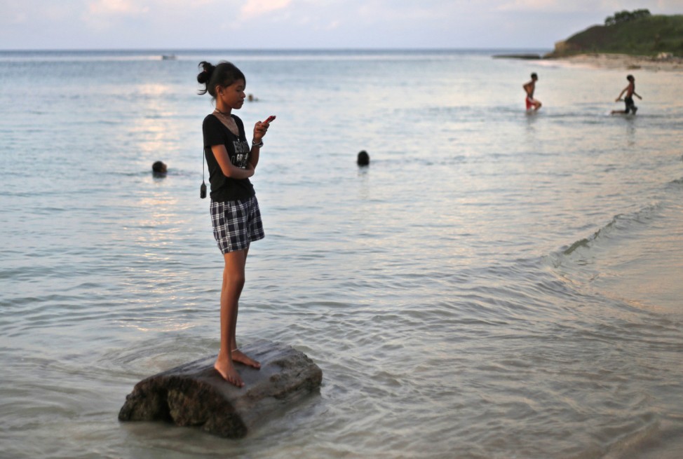 A girl chats on her mobile phone on a beach in Dobo, Aru Islands, Indonesia