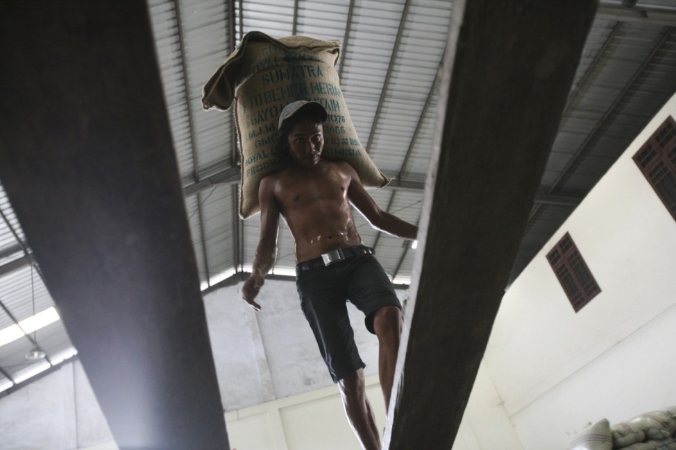 A worker loads a sack of coffee beans into a container for shipping to markets in Medan, North Sumatra, Indonesia,
