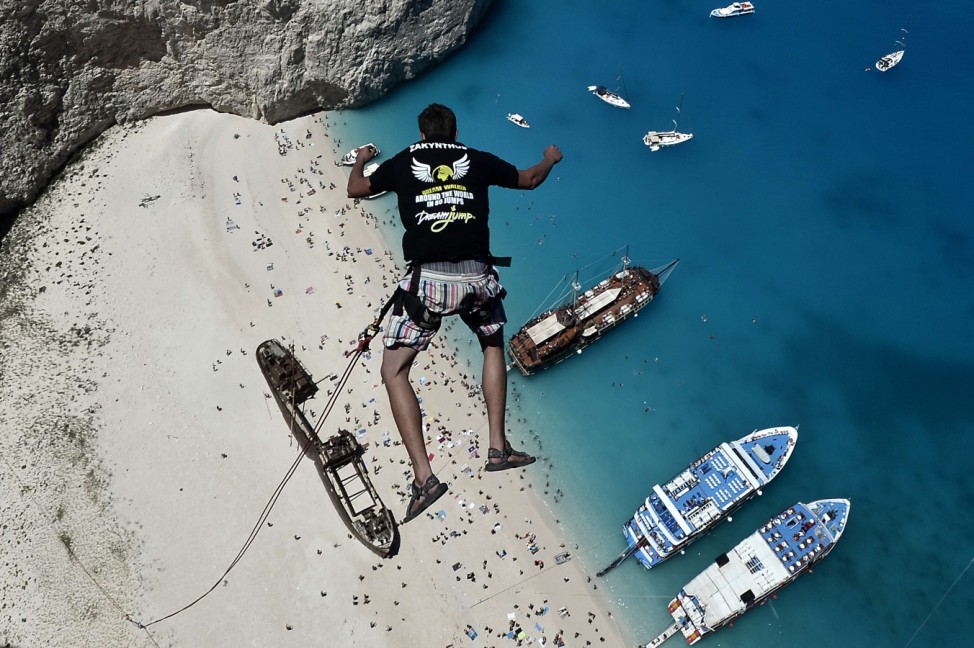 Lukas Michul, a member of the 'dream walker' group jumps from atop the rugged rocks overlooking the azure waters of Navagio beach, one of the Greece's most renowned leisure spots on the popular touri