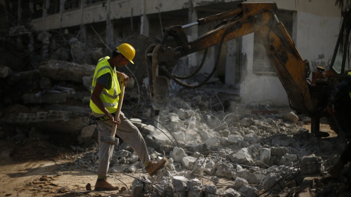 Palestinian worker carries a hammer as he participates in efforts to clear the rubble of a school in the east of Gaza City