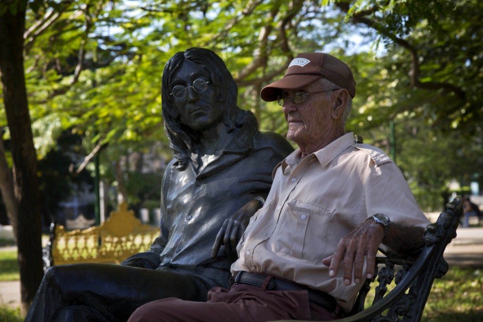 Juan Gonzalez, poses for a photo next to the bronze statue of the late Beatle John Lennon in Havana, Cuba,